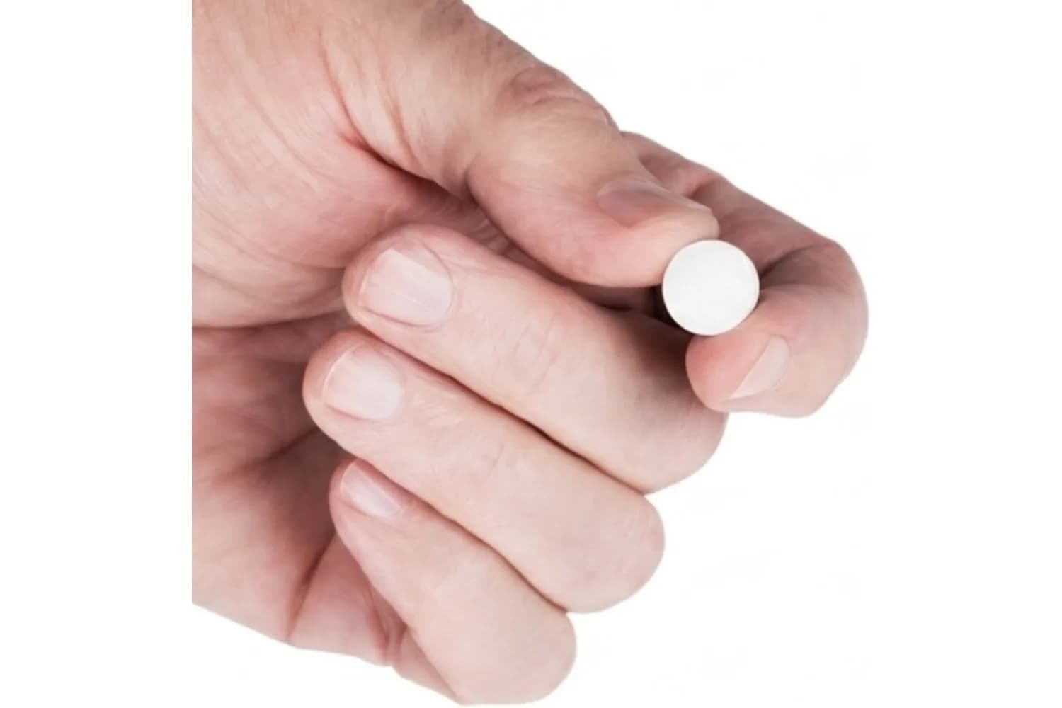 Una mano sostiene entre los dedos una pastilla XyliMelts, del tamaño de una moneda pequeña